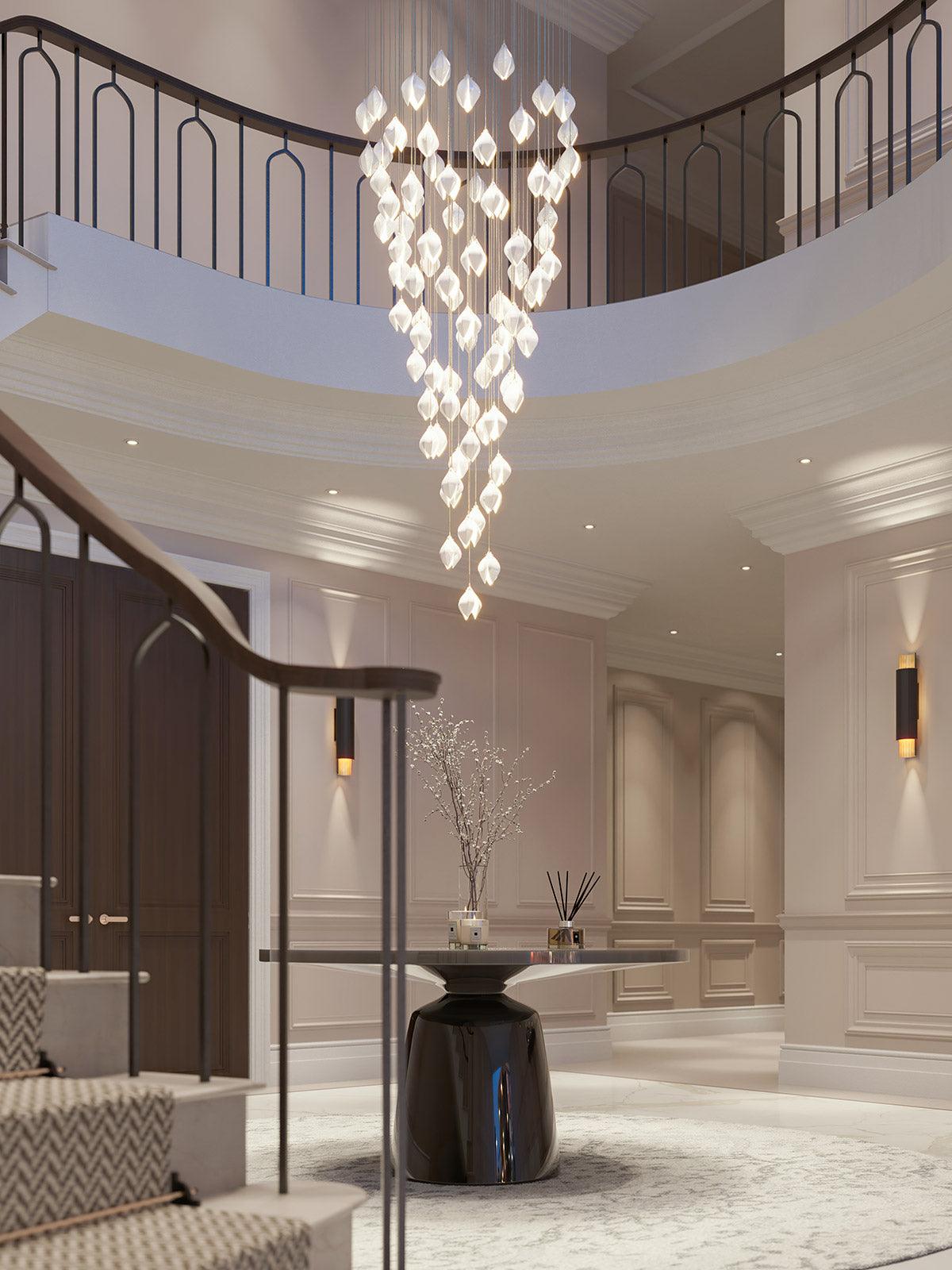 Tall white flower-bud cascade in a curved stair void above a round glass hall table