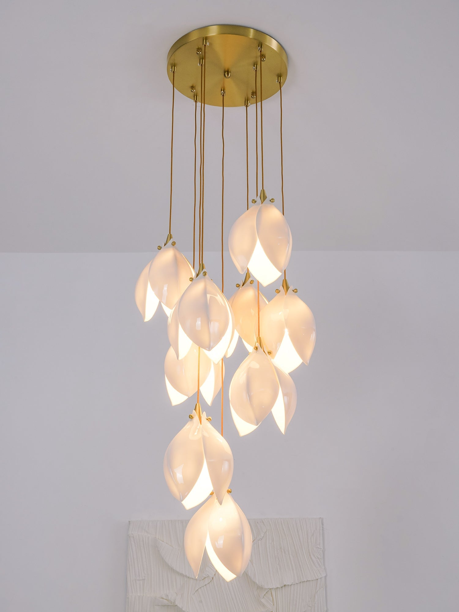 Ten glowing white petal buds below a round gold-tone canopy in a pale room