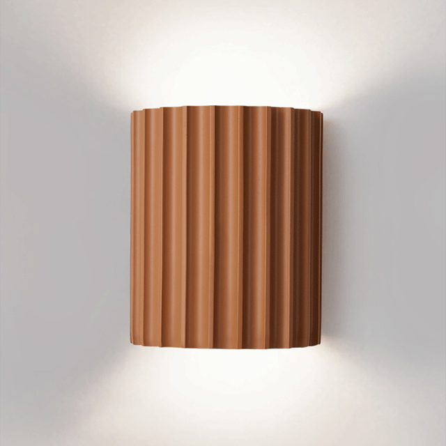 Close front view of an orange curved ribbed wall light with glow above and below