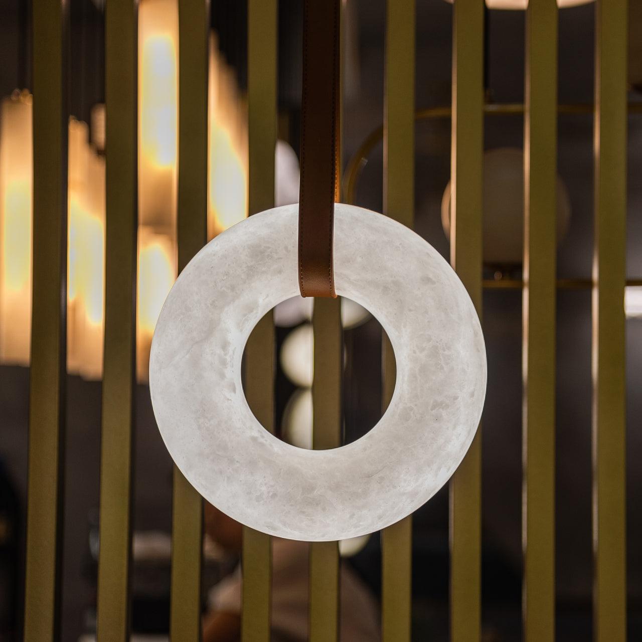 Unlit vertical alabaster ring in front of gold-coloured slats.