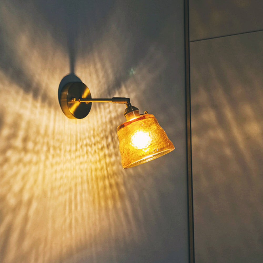 Angled lit orange shade casting textured warm-looking light on wall beside vertical panel