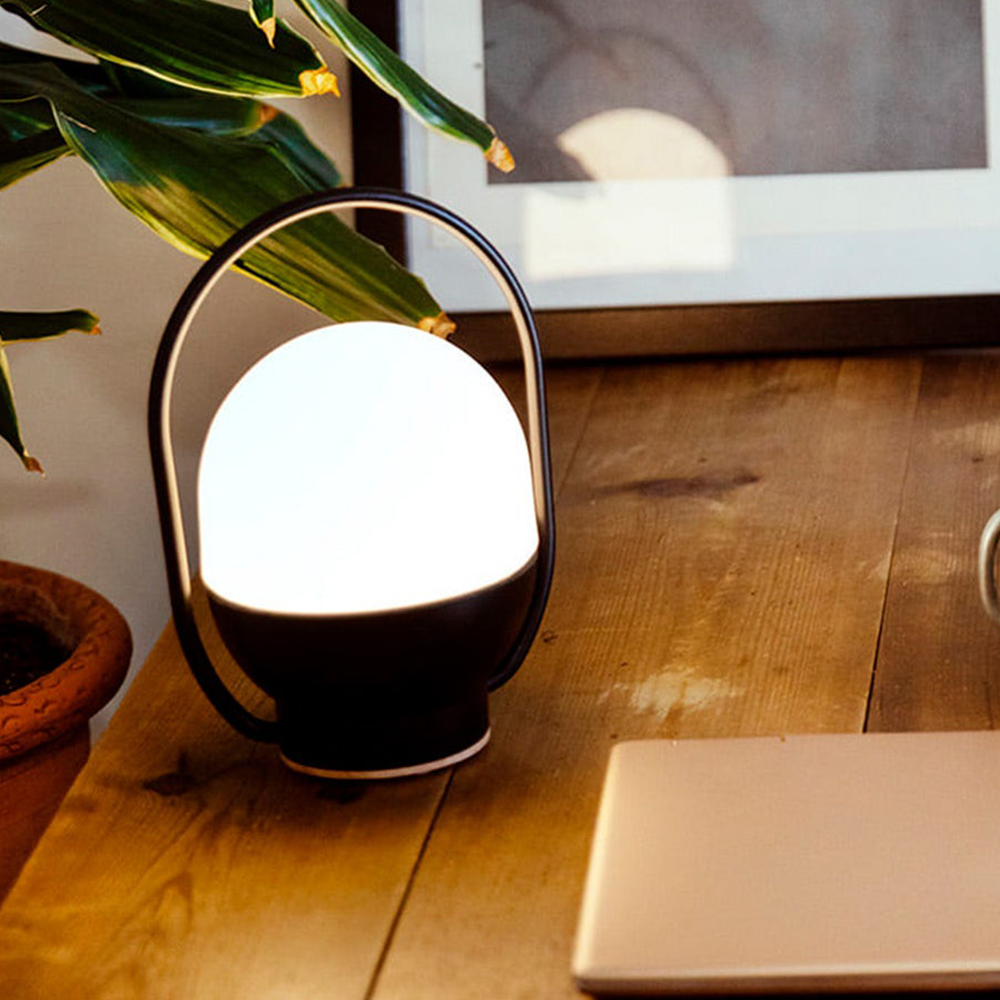 Illuminated black-and-white lamp beside a laptop