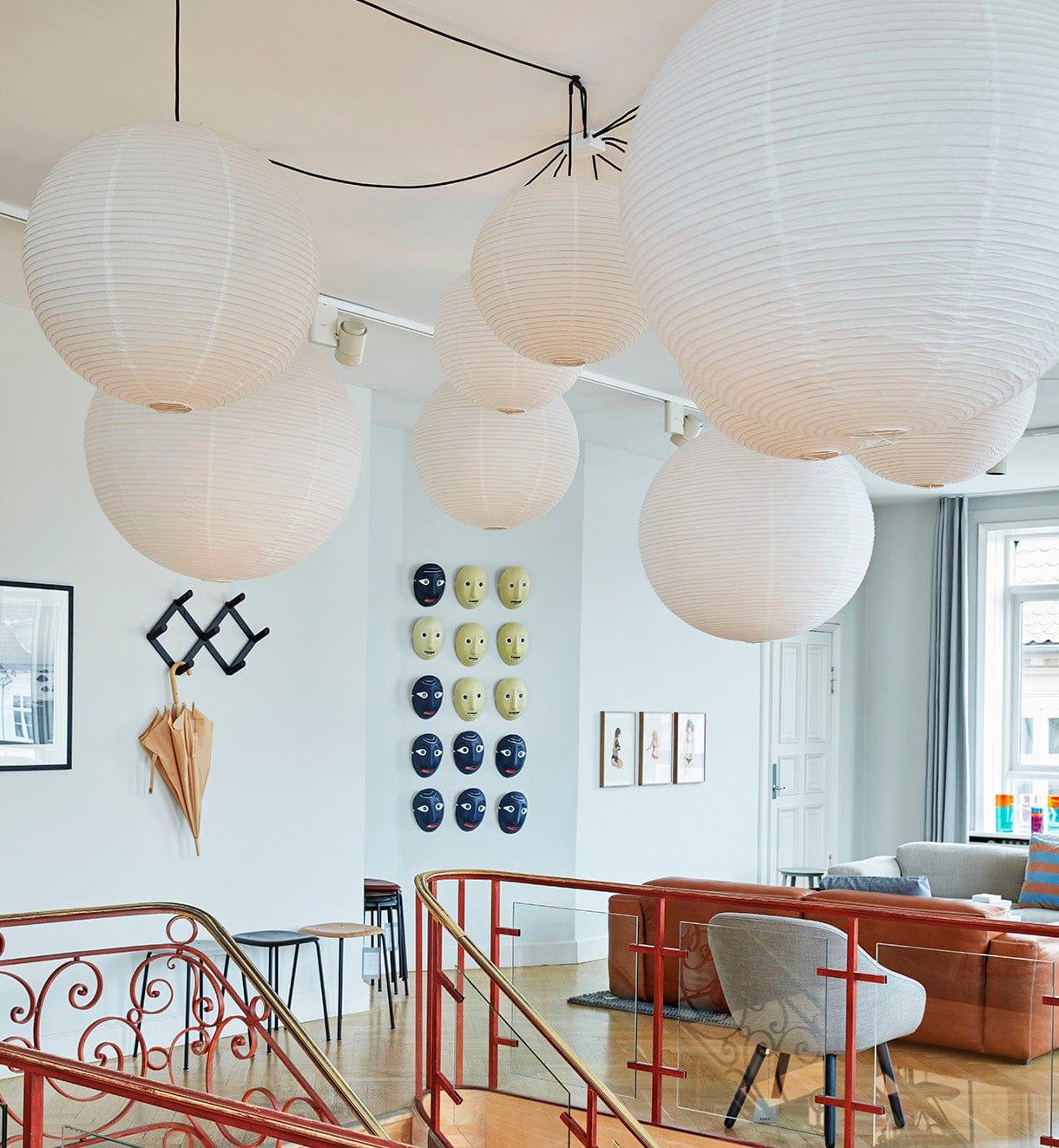 Several paper globes above an open lounge and ornate red stair railing with cords crossing the ceiling