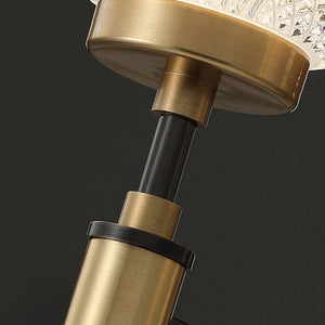 Close-up of gold cylindrical fittings and a dark upright stem beneath the patterned shade