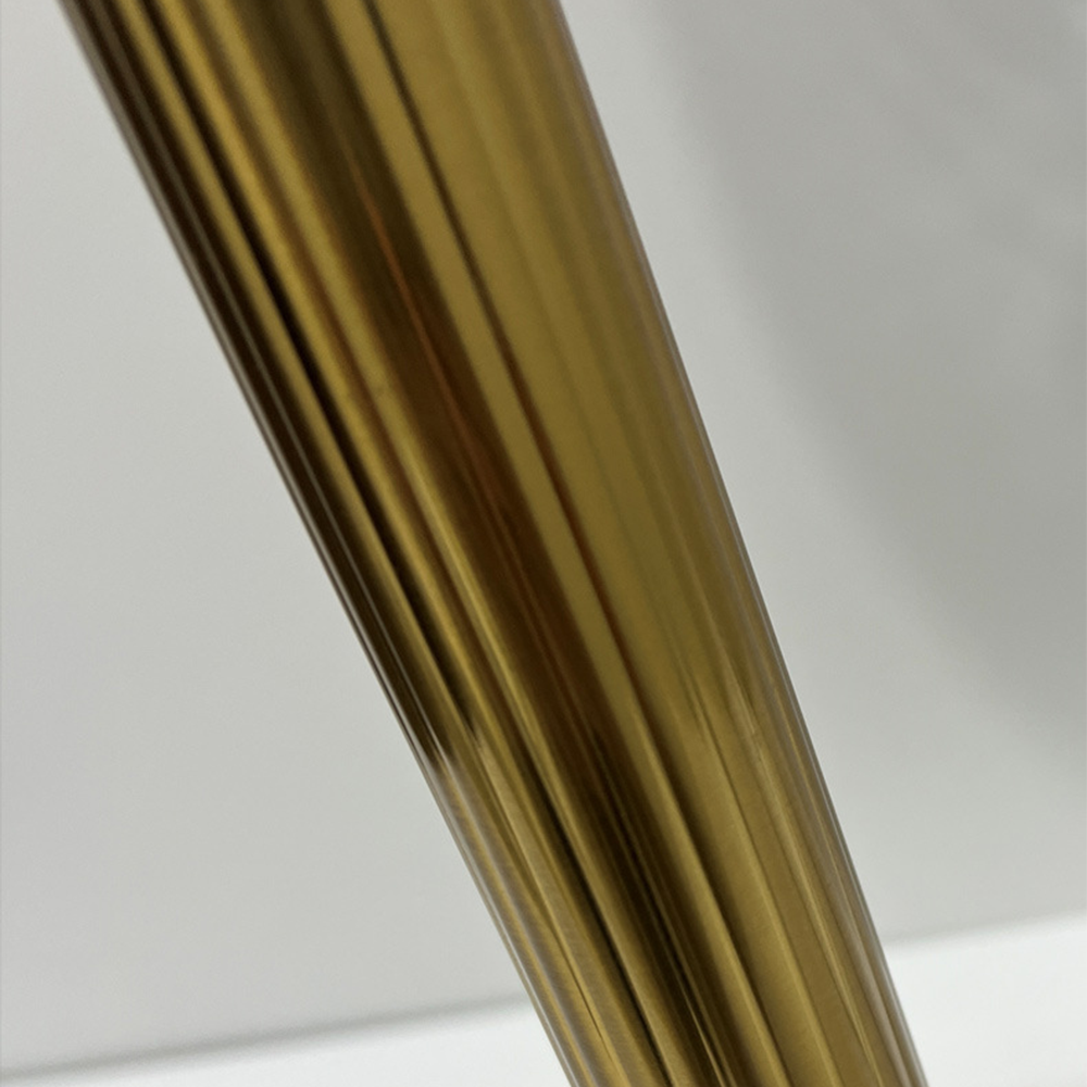 Close view of the gold-tone column’s vertical flutes and reflective ridges against a pale background