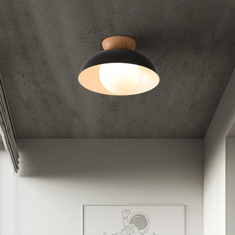 Black close-mount ceiling light with a wood upper piece and glowing round face under a metal dome