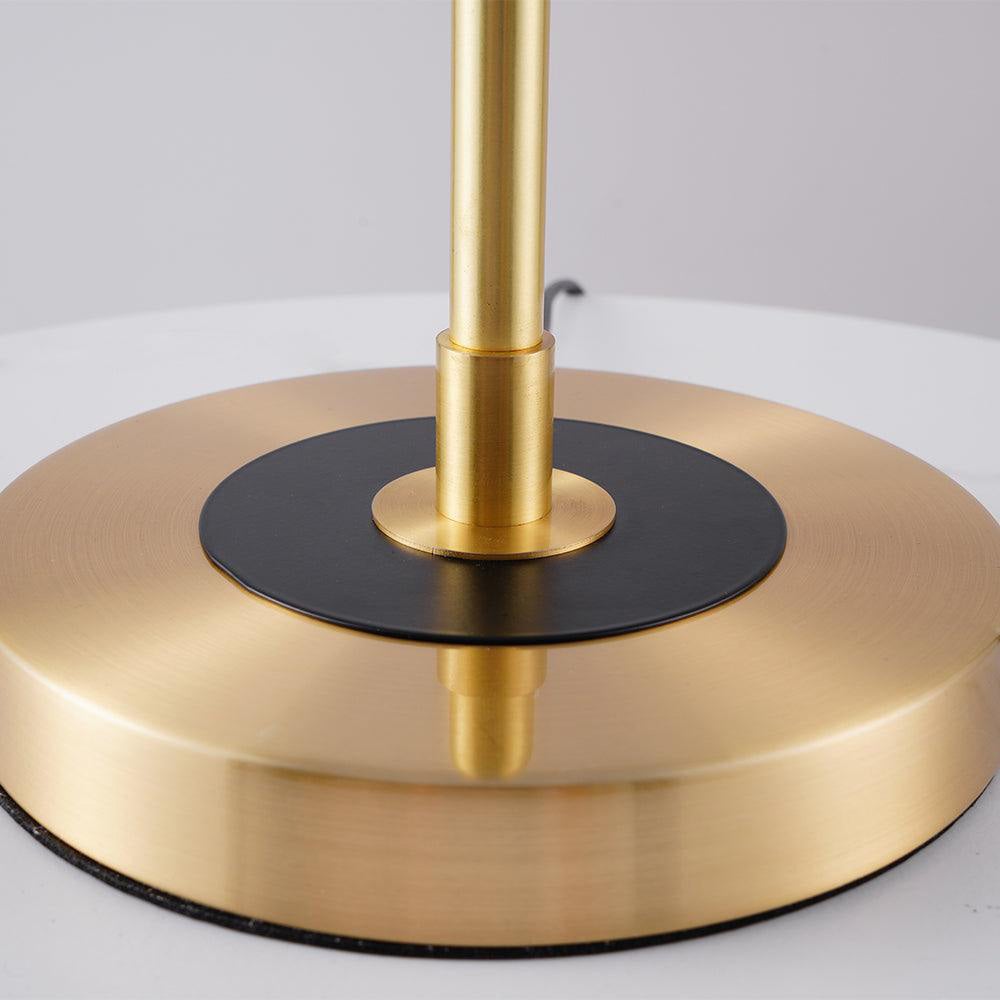 Close-up of gold-toned circular lamp base with black centre ring, stem collar and cord behind