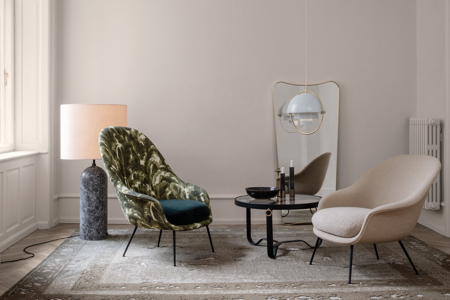 White ring pendant above a side table between two lounge chairs.