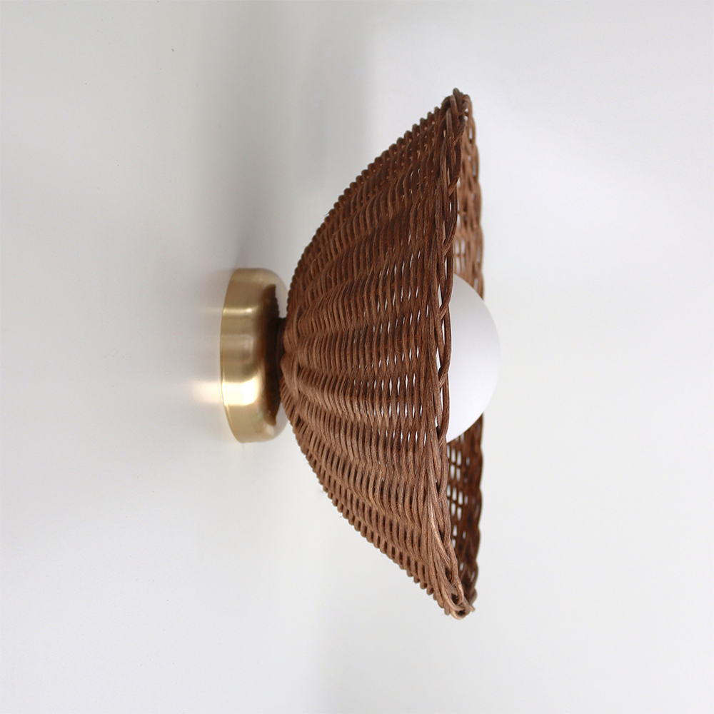 Side close-up of dark woven flared shade, white glass globe and gold-tone rear plate