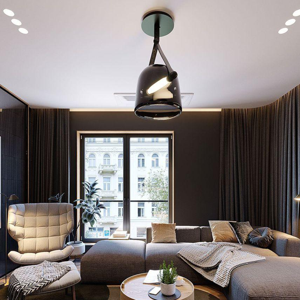 Smoked glass pendant with black strap and round canopy above grey seating beside a cream chair and curtains