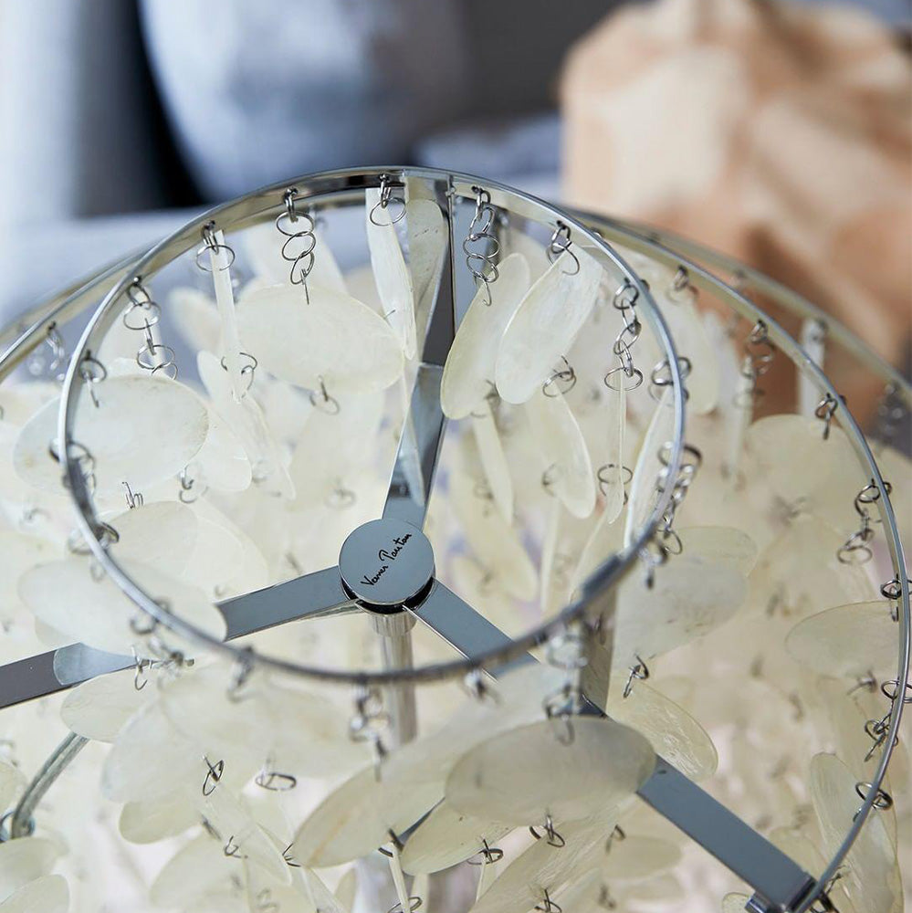 Overhead view of silver-toned lamp rings, spokes, central cap and linked hanging pale shell discs