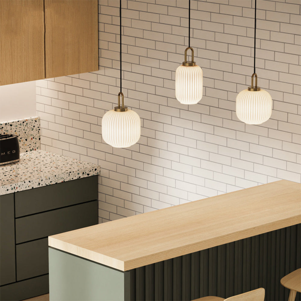 Three white ribbed glass pendants in different profiles above a wooden kitchen counter