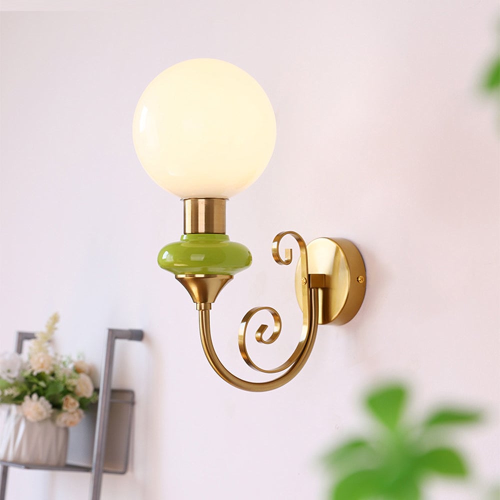 Illuminated gold-and-green globe wall light by flowers
