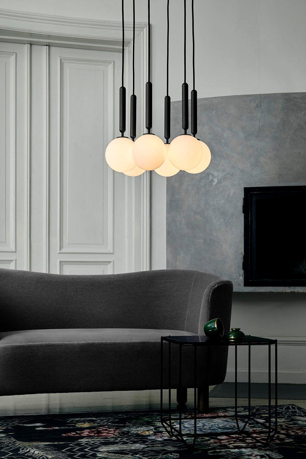 White globes hanging from black stems above a sofa