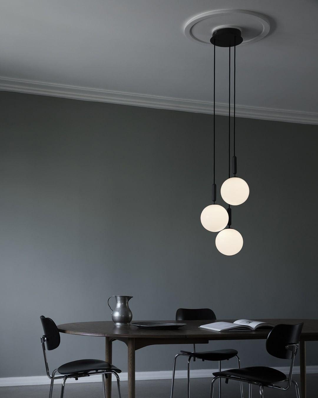 Three white globes hanging below a black round canopy
