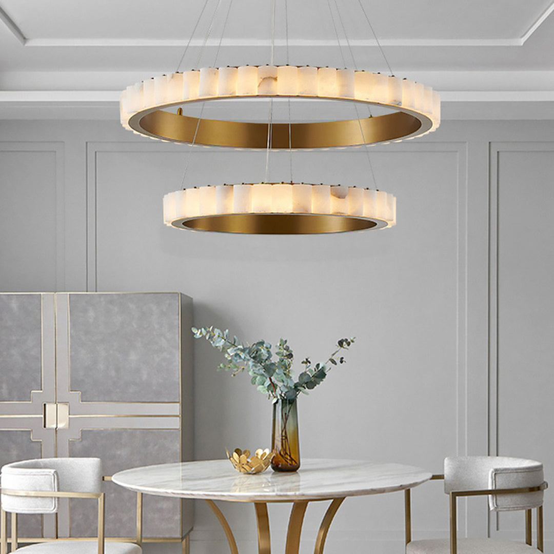 Two gold-tone-band segmented rings above a pale round dining table against a panelled wall