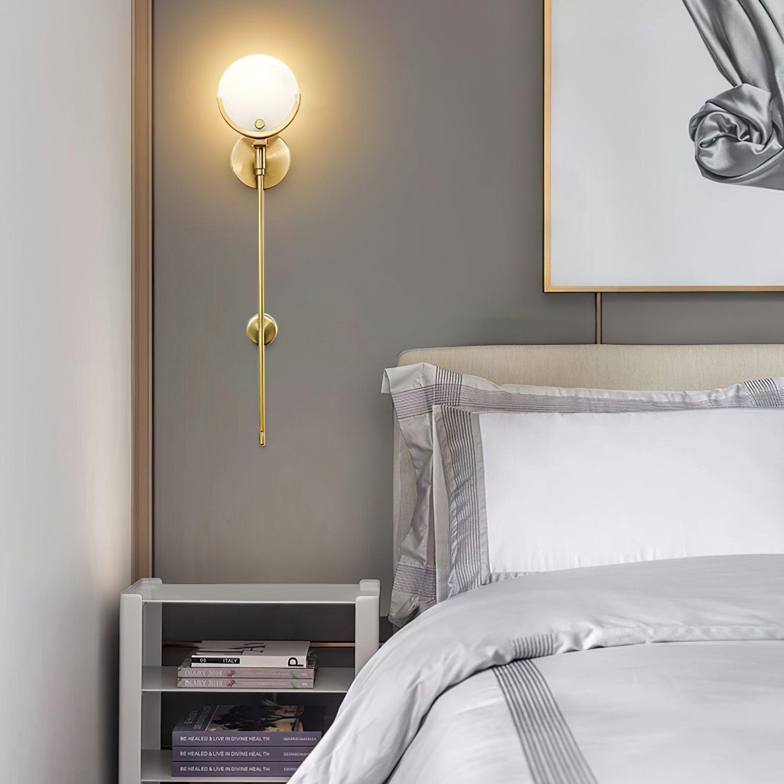 Universal Ava white globe wall light glowing beside a bed