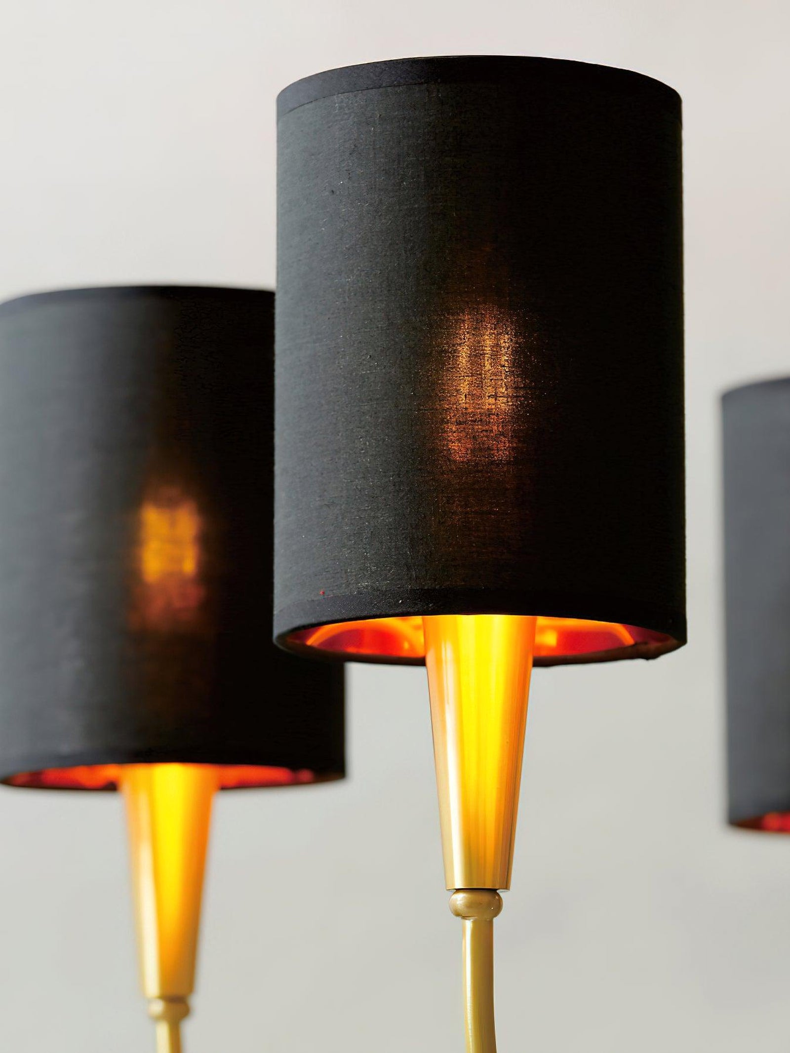 Close view of Quincy black woven cylindrical shade with warm-looking underside and gold-tone tapered holder