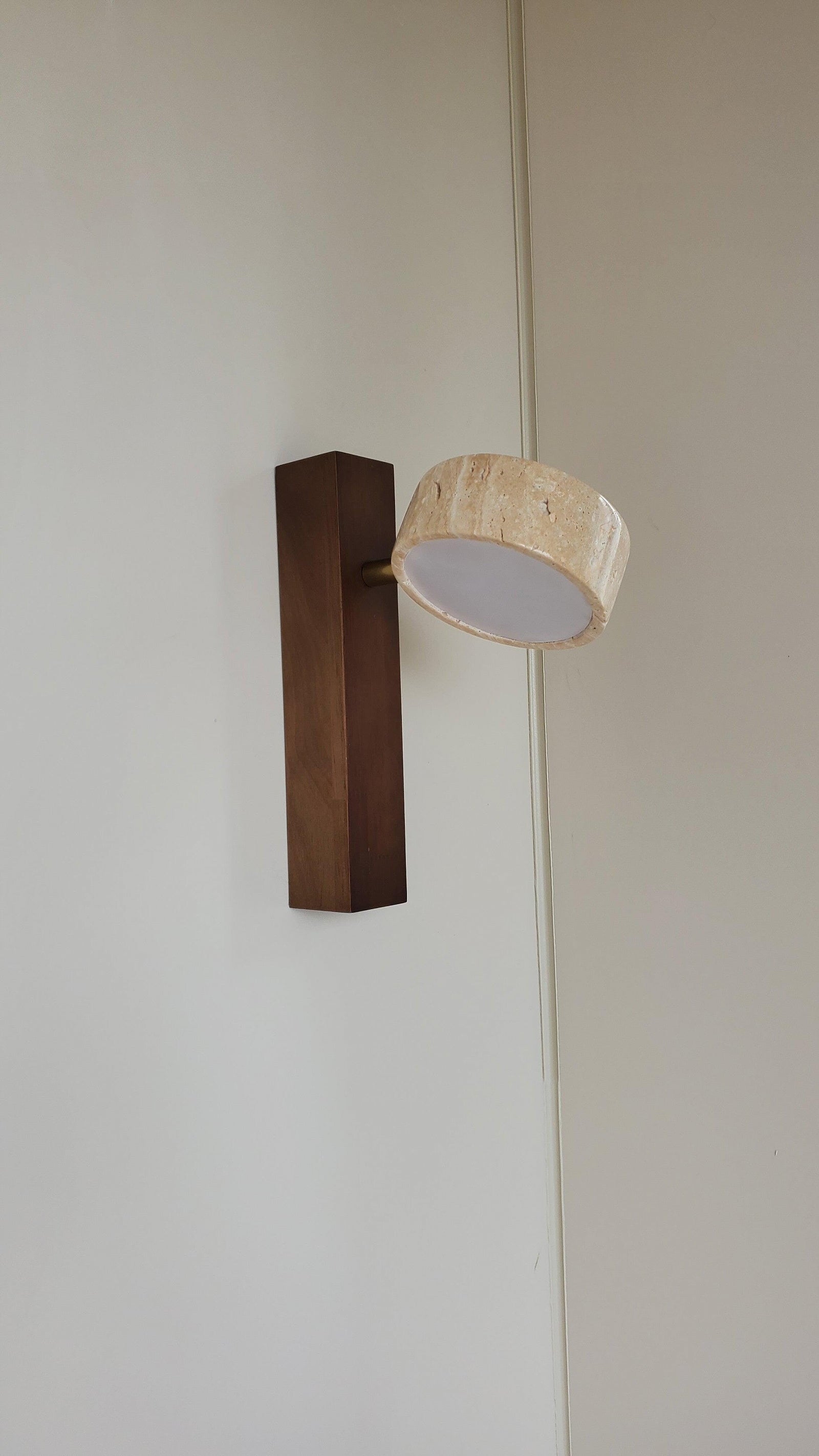 Unlit travertine shade beside a dark rectangular wooden plate