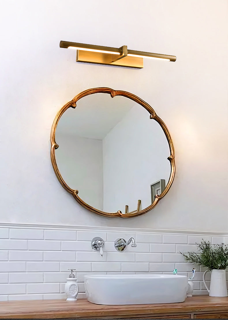 Brass-colour picture light above an ornate round mirror and basin on a wooden countertop