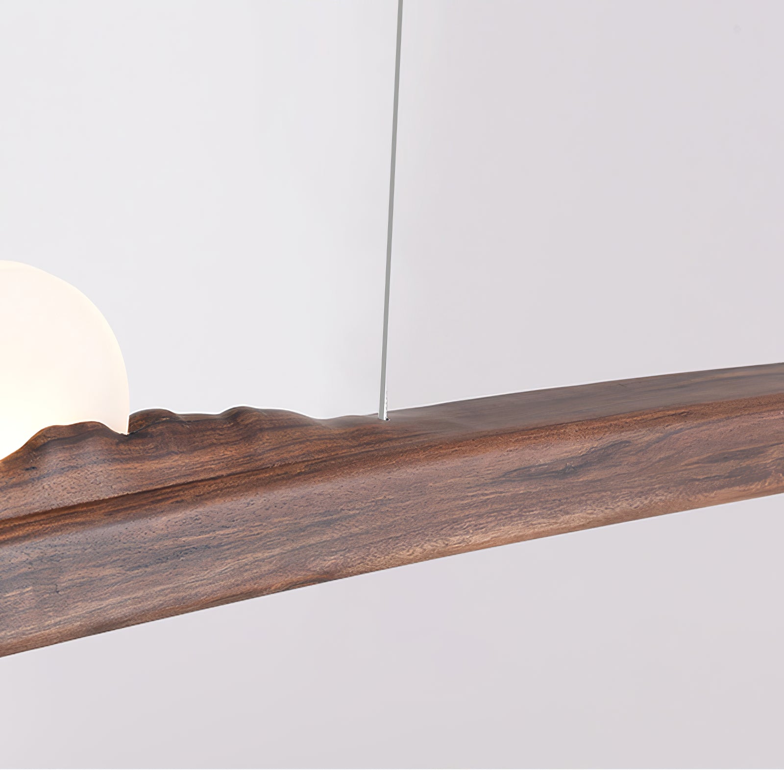 Close-up of dark wood grain, central ridge, cable attachment and edge of the white globe-like element