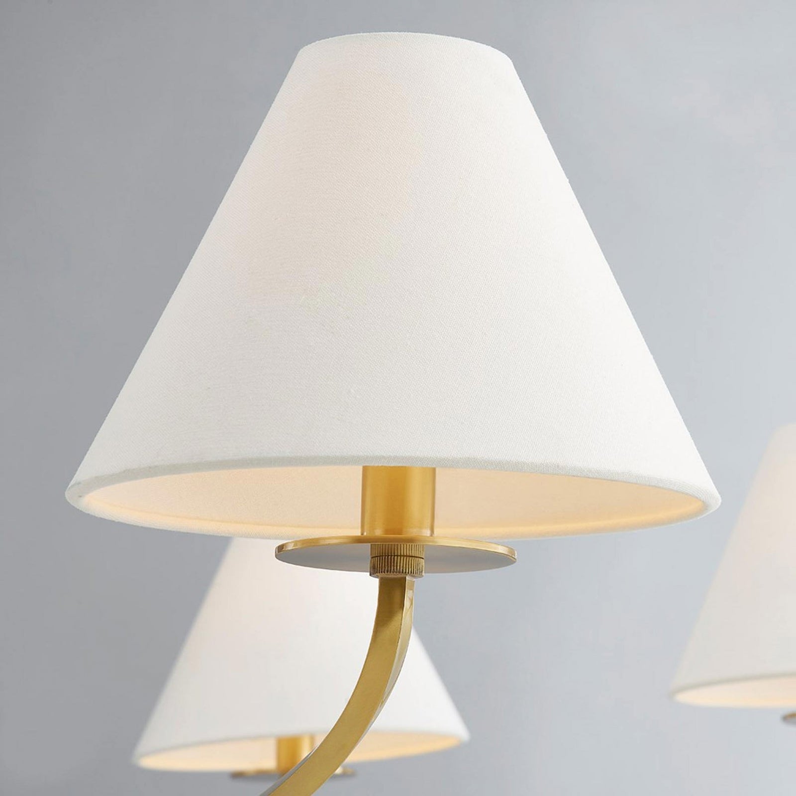 Close-up of Stacey white fabric shade with warm interior, gold-tone dish, curved arm and ribbed fastener