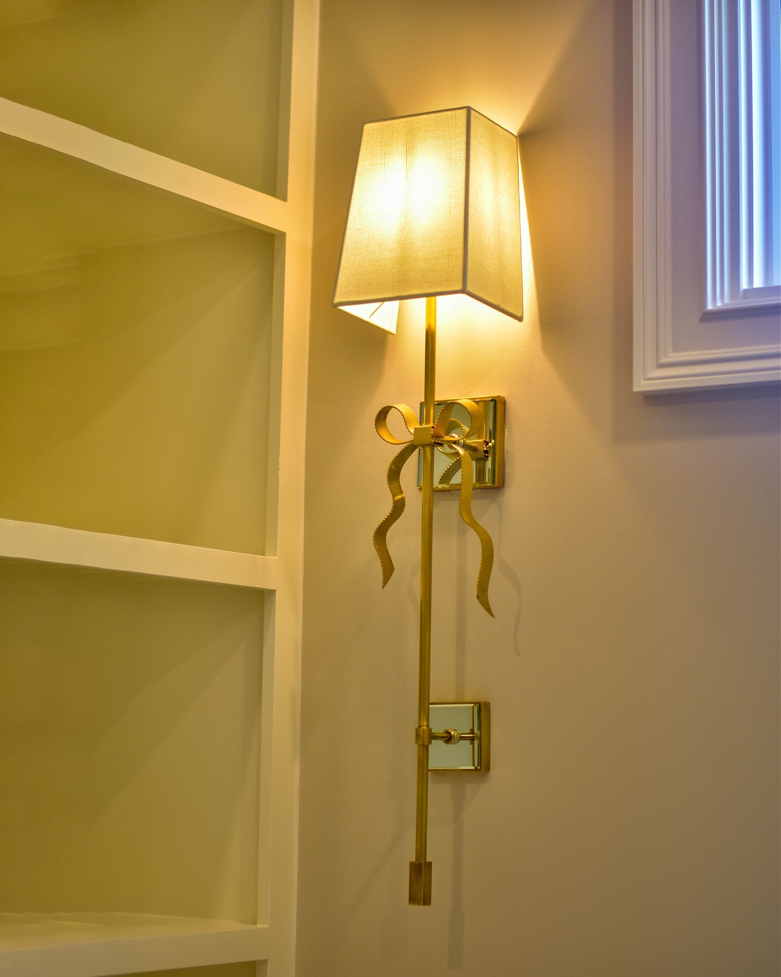 Angled view of Ellery glowing tapered shade and long tail near a window
