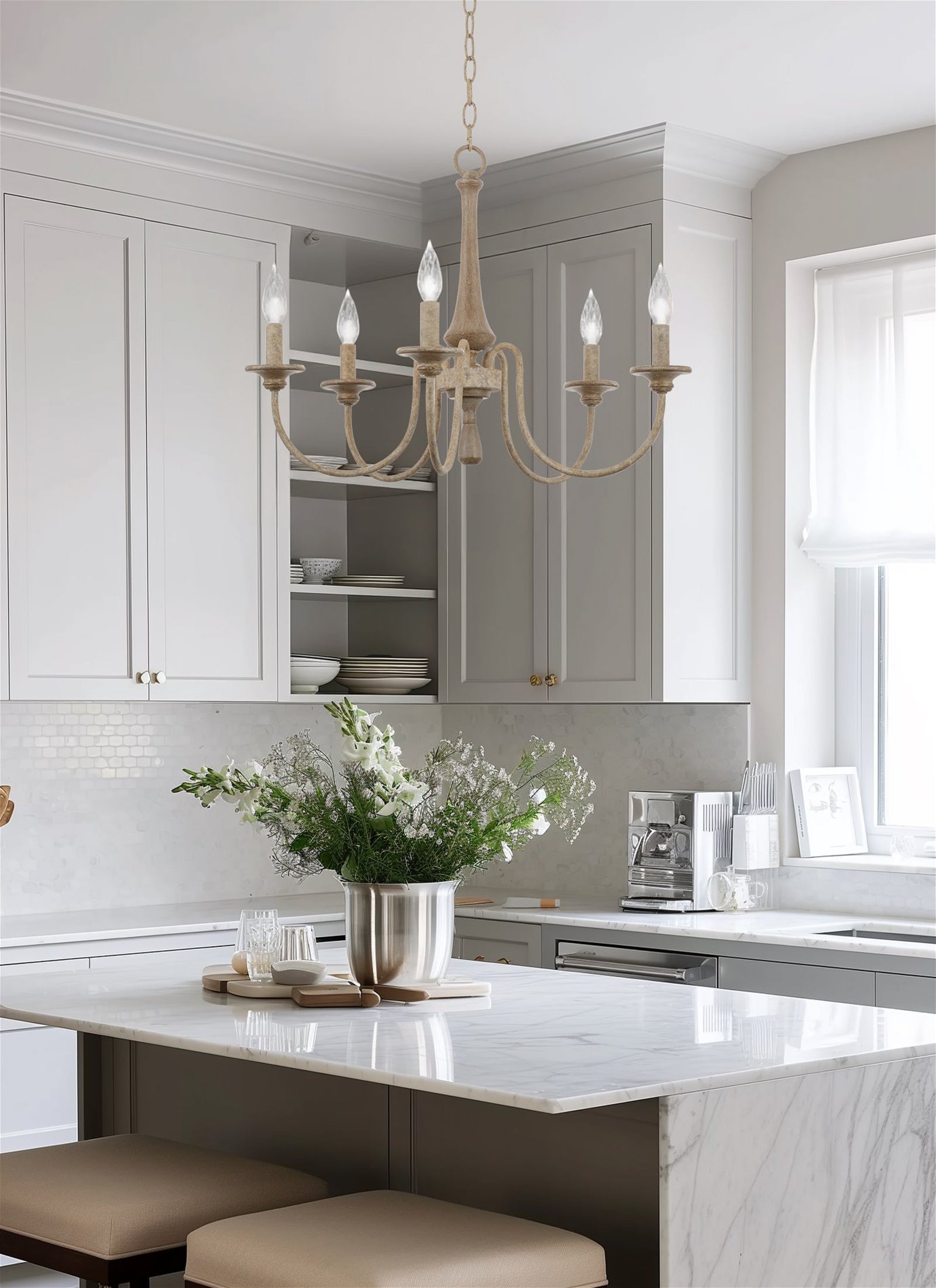 Pale five-light chandelier above a kitchen island with flowers, gray cabinets and a coffee maker