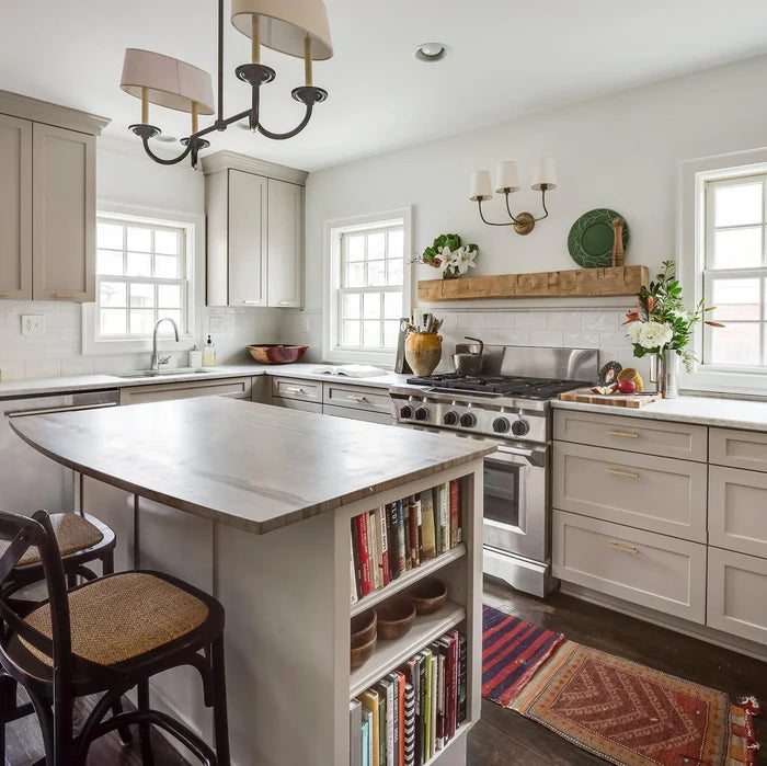 Small single wall lights in a kitchen with an island and overhead chandelier.
