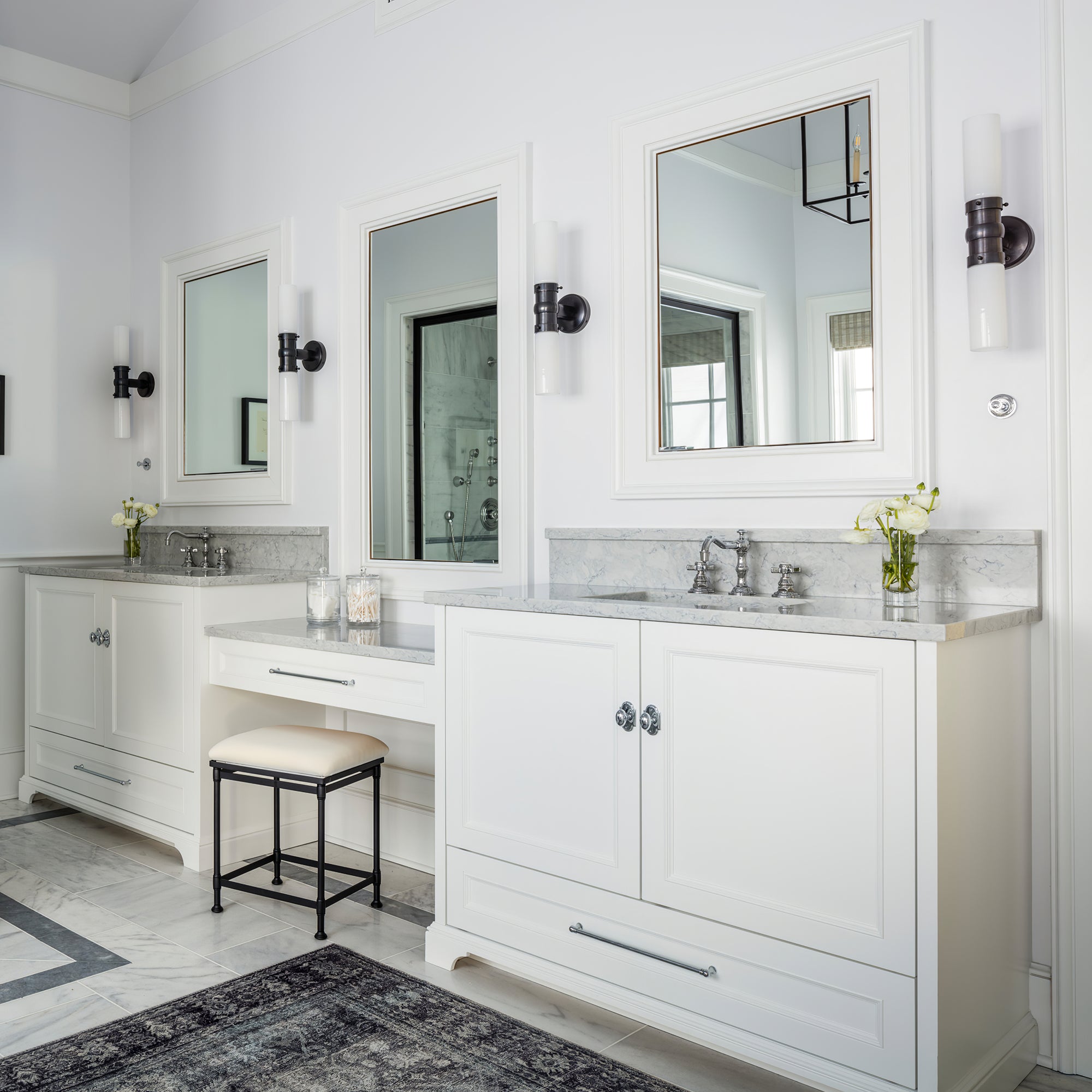 Four dark-centred double white-glass wall lights arranged across bathroom mirrors above a white vanity