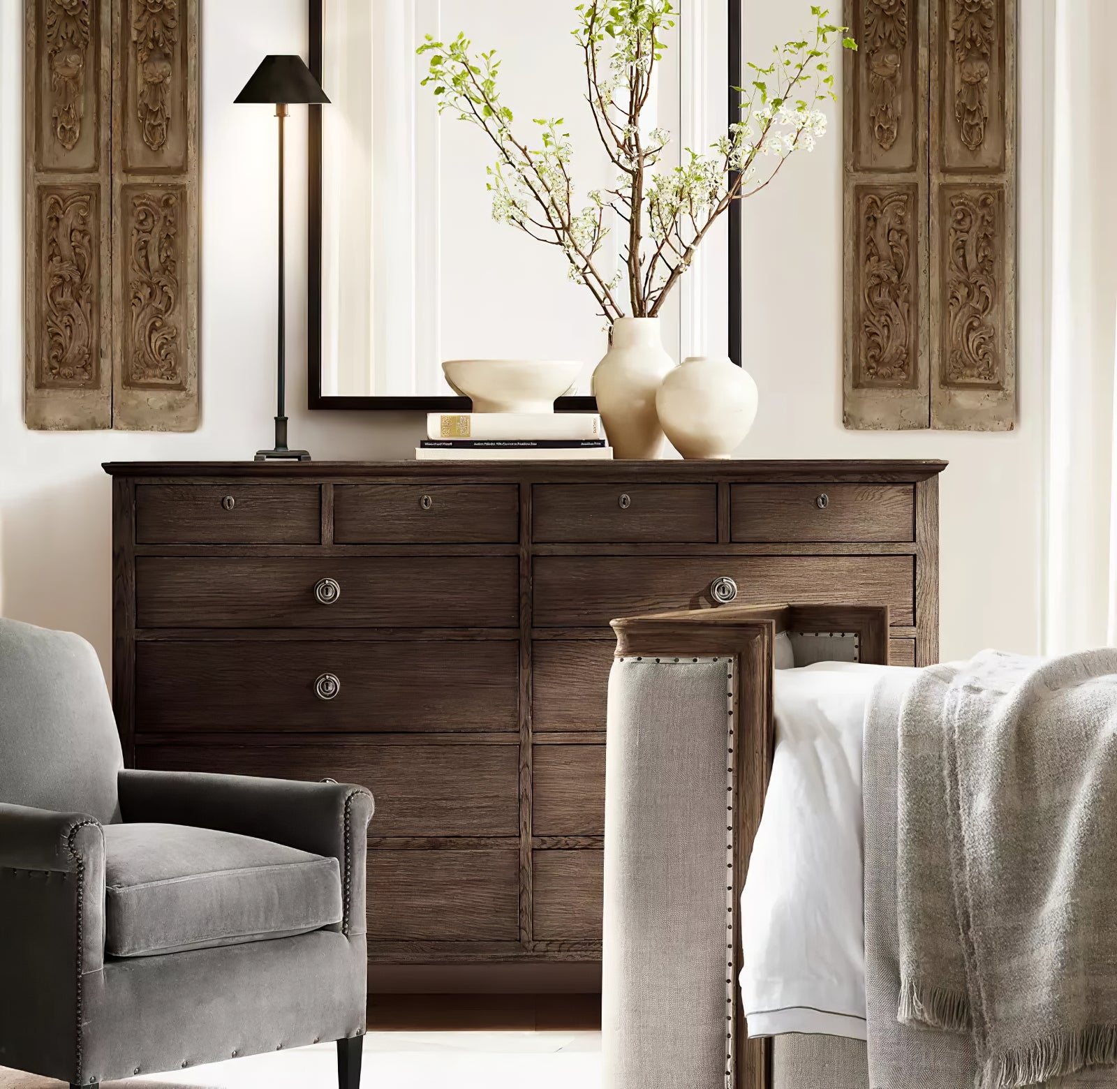 Dark-shade Slim Candlestick lamp on chest beside books and pale vases with flowering branches before mirror