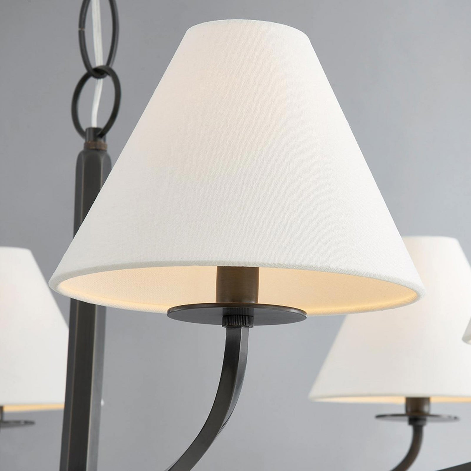 Close-up of Stacey white fabric shade glowing inside above black dish and curved arm with chain behind