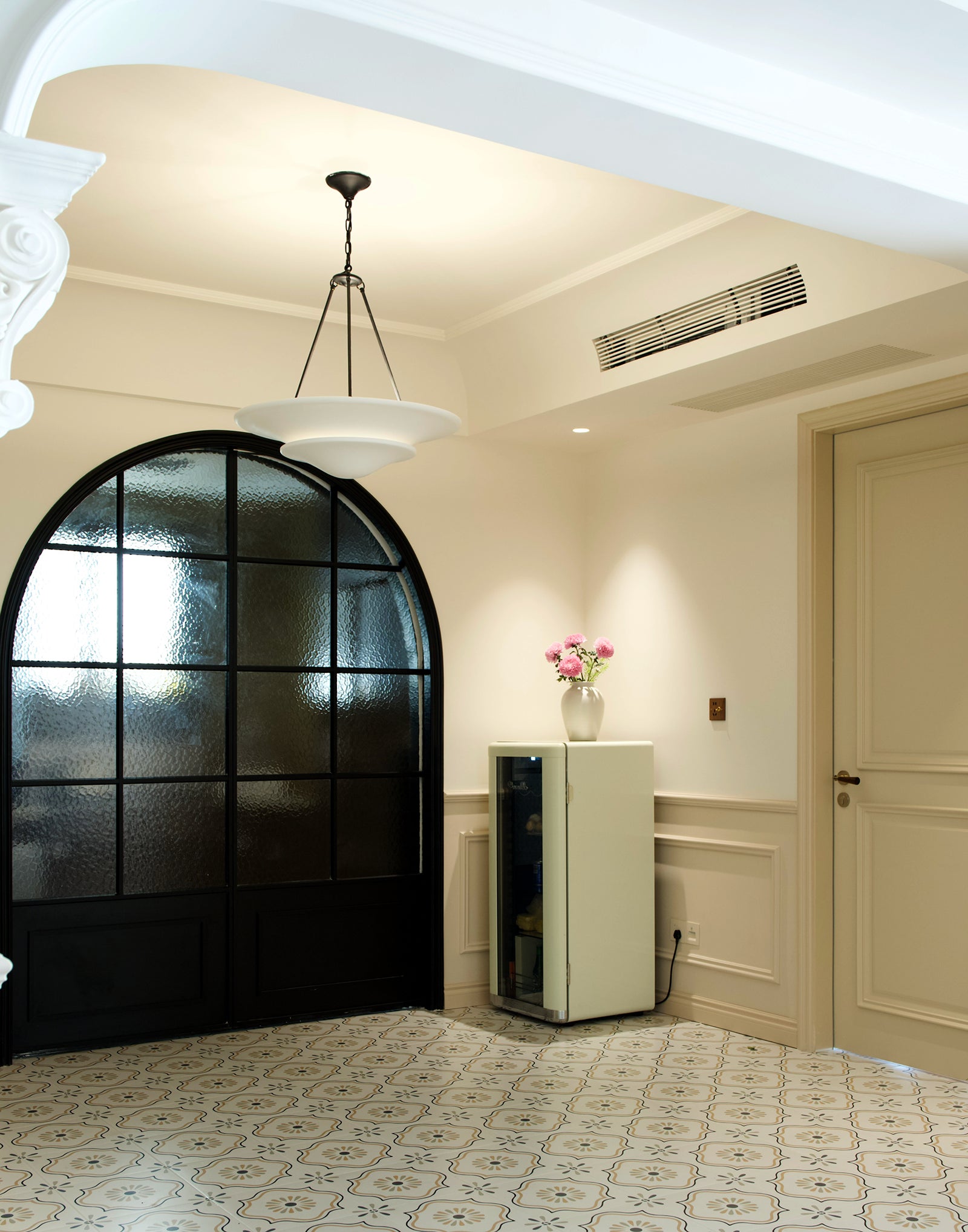 White Mollino bowls with black suspension before arched glass door beside wine cabinet and pink flowers