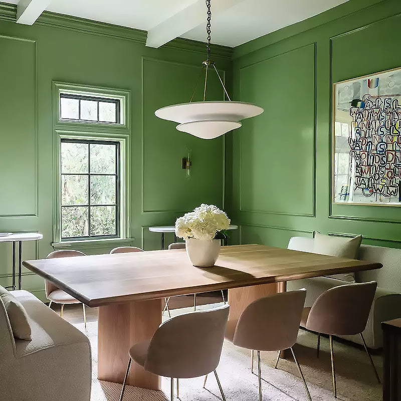 White Mollino bowl chandelier with gold-tone supports above wooden dining table in green panelled room