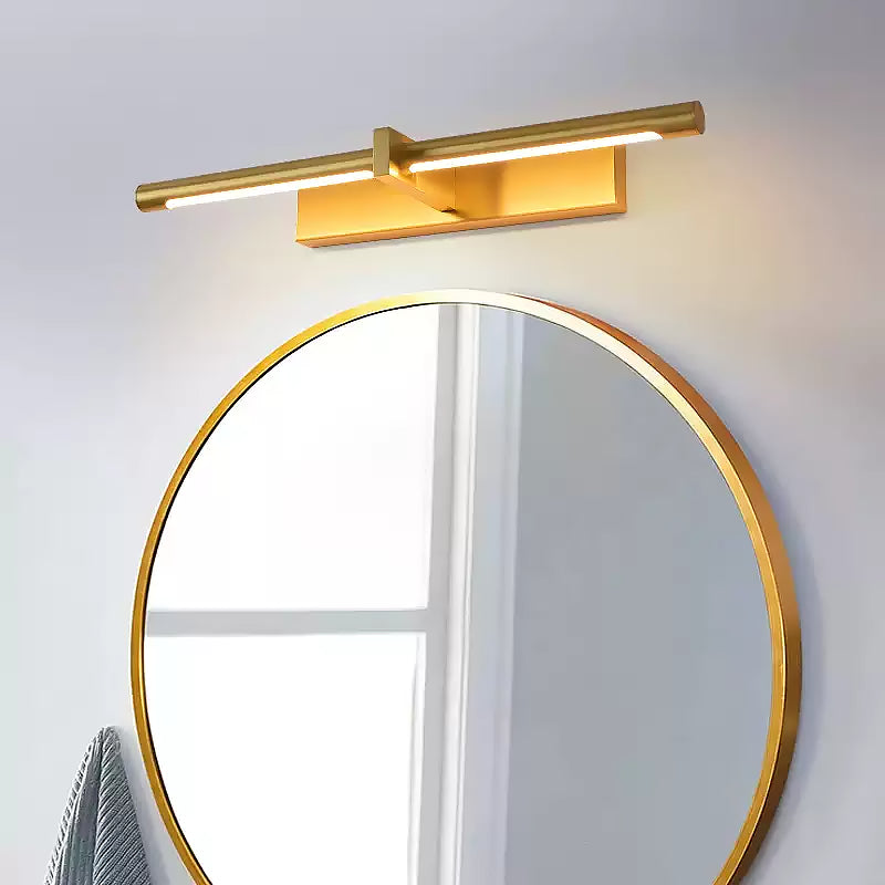 Close brass-colour picture light with underside diffuser above a round gold-rimmed mirror by a window