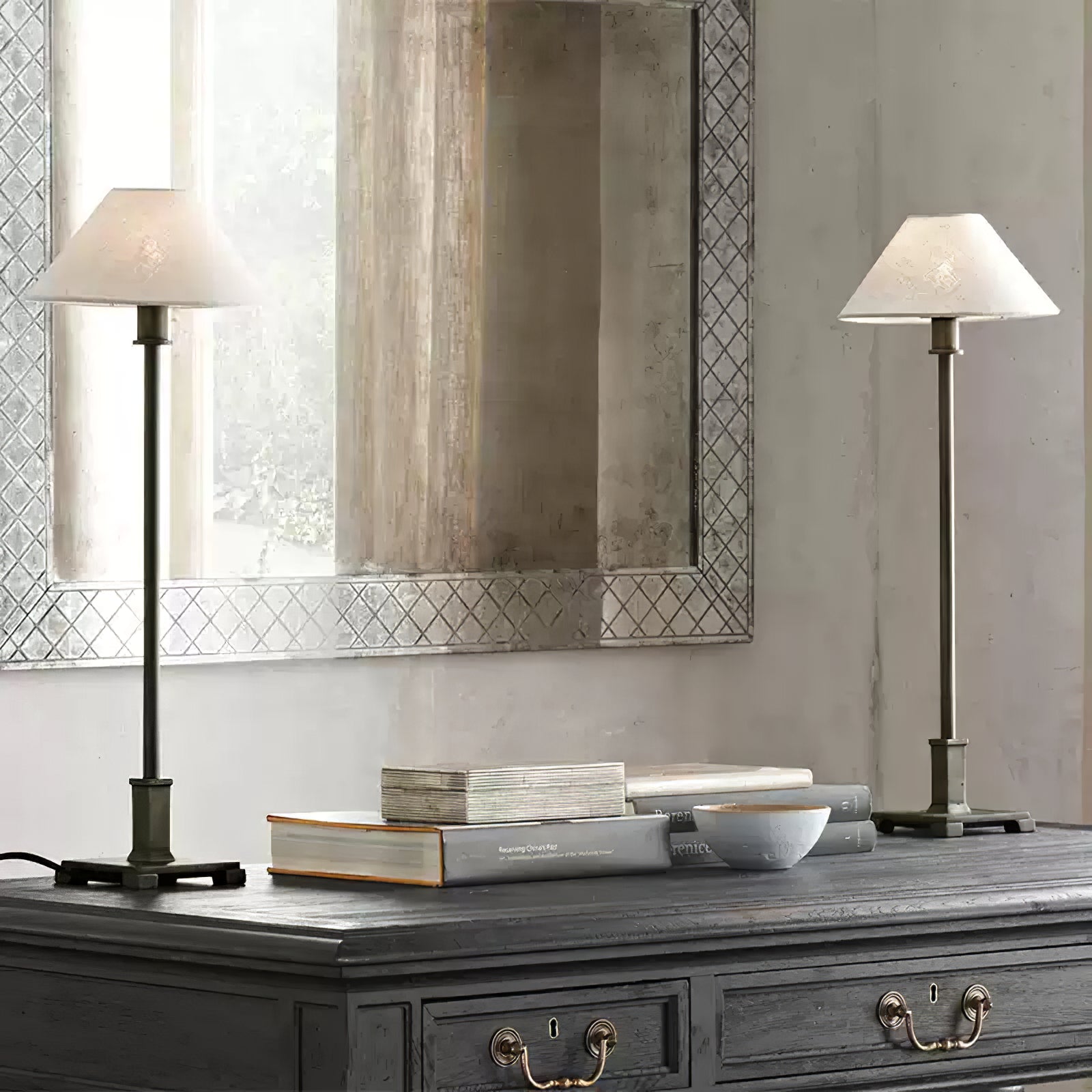 Close view of two light-shade Slim Candlestick lamps with stepped square bases and visible left cord on grey cabinet