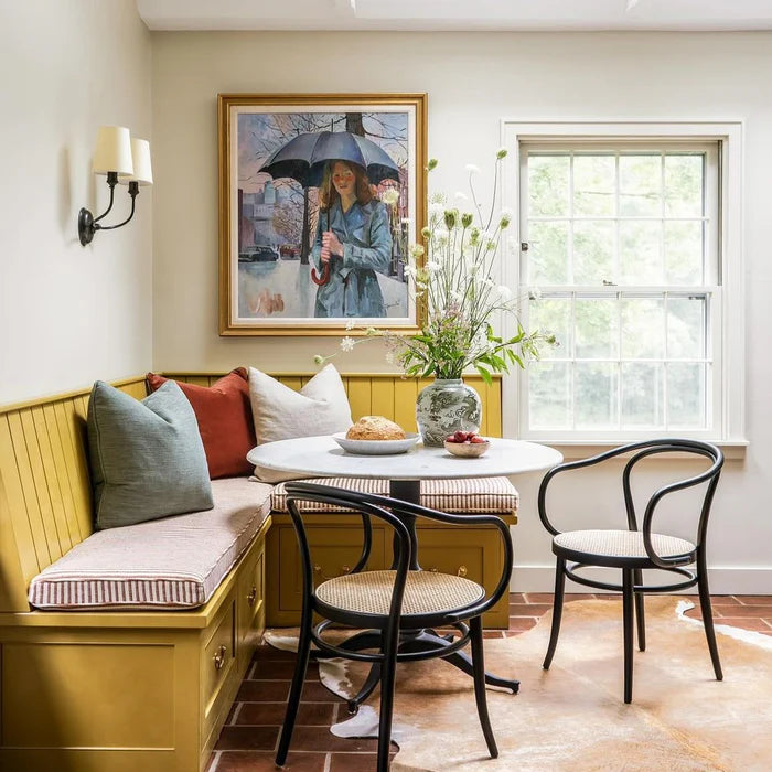 Curved-arm wall lighting above a breakfast nook with a round table.