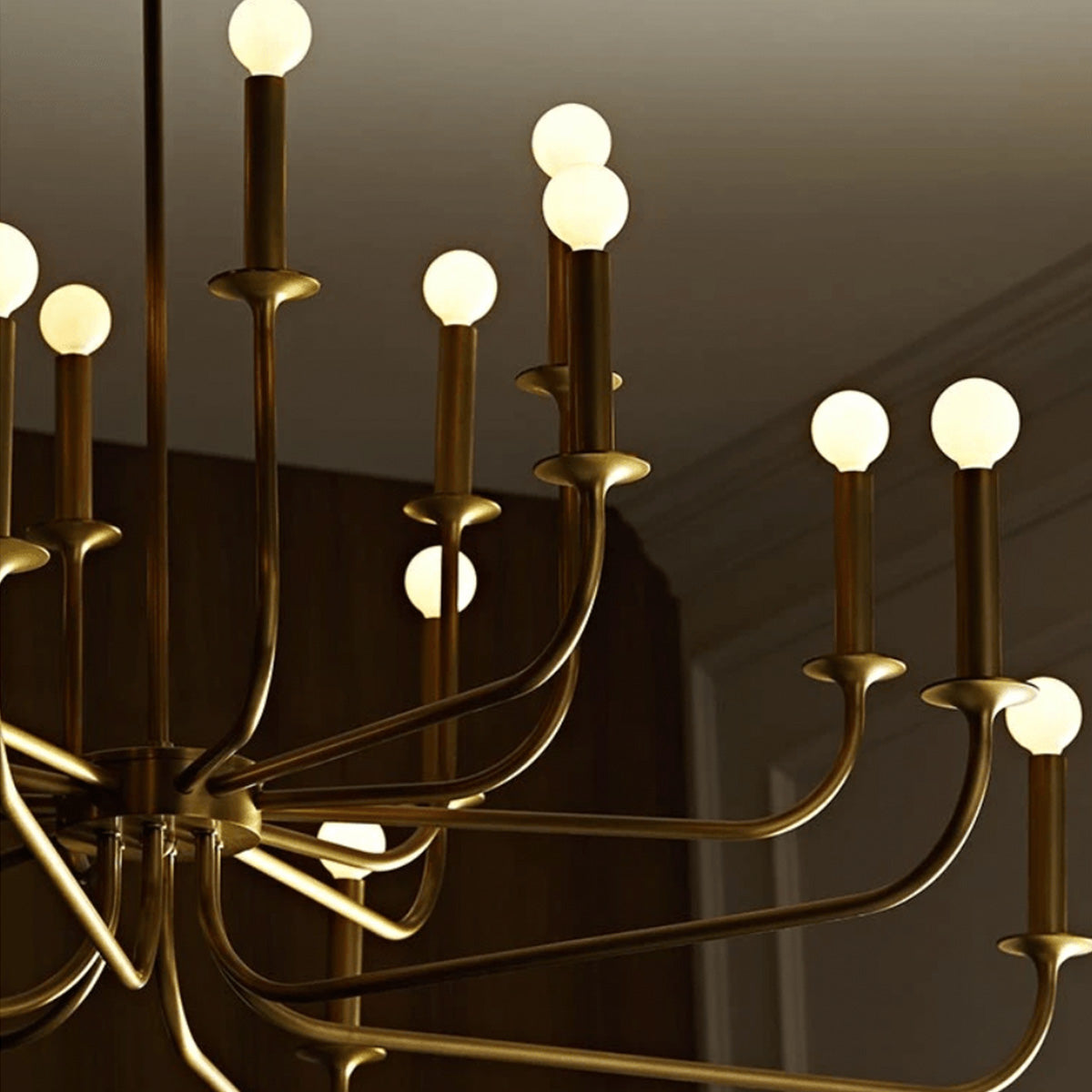 Close view of glowing round bulbs above gold candle-style holders and curved chandelier arms