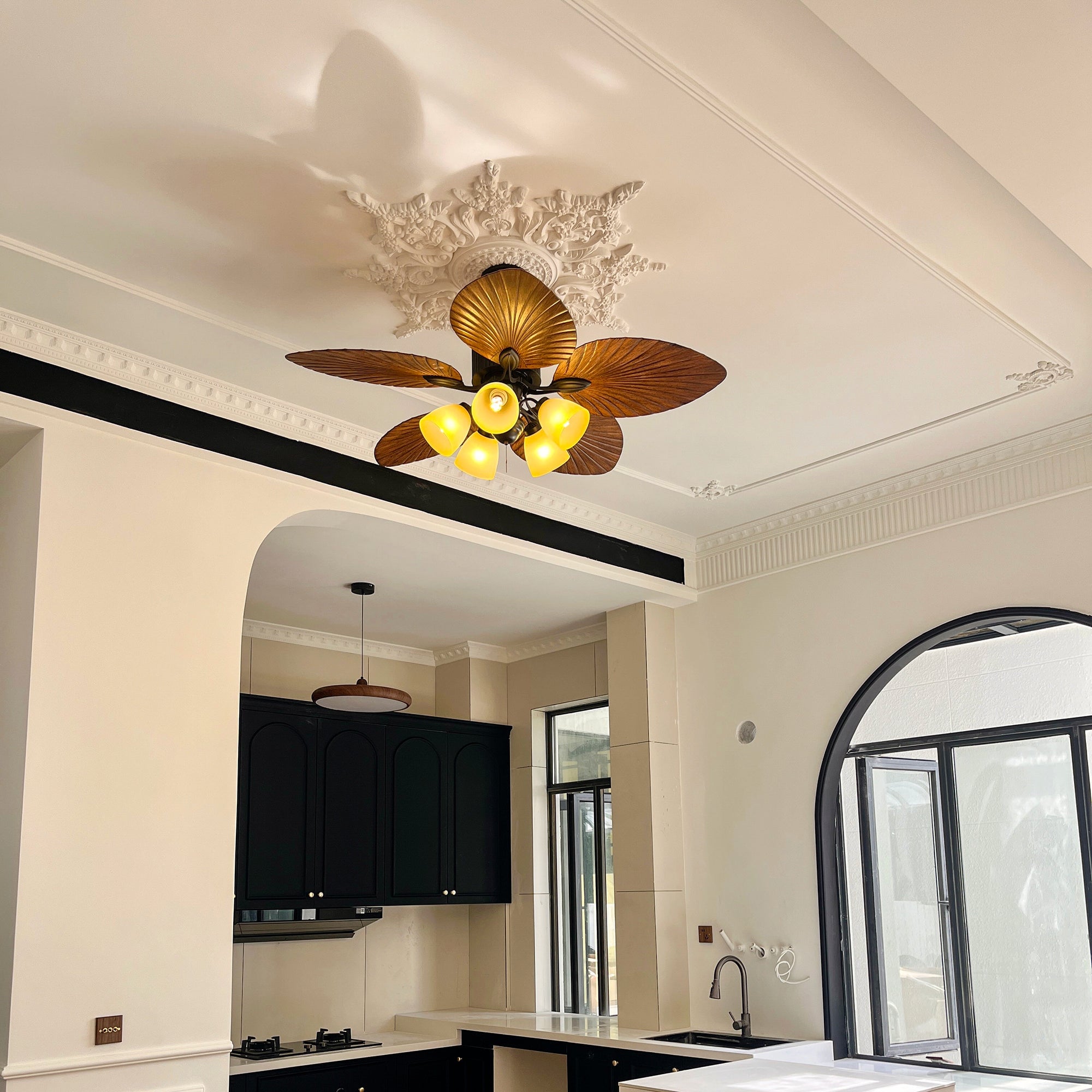 Leaf-pattern fan light above a television and dining area