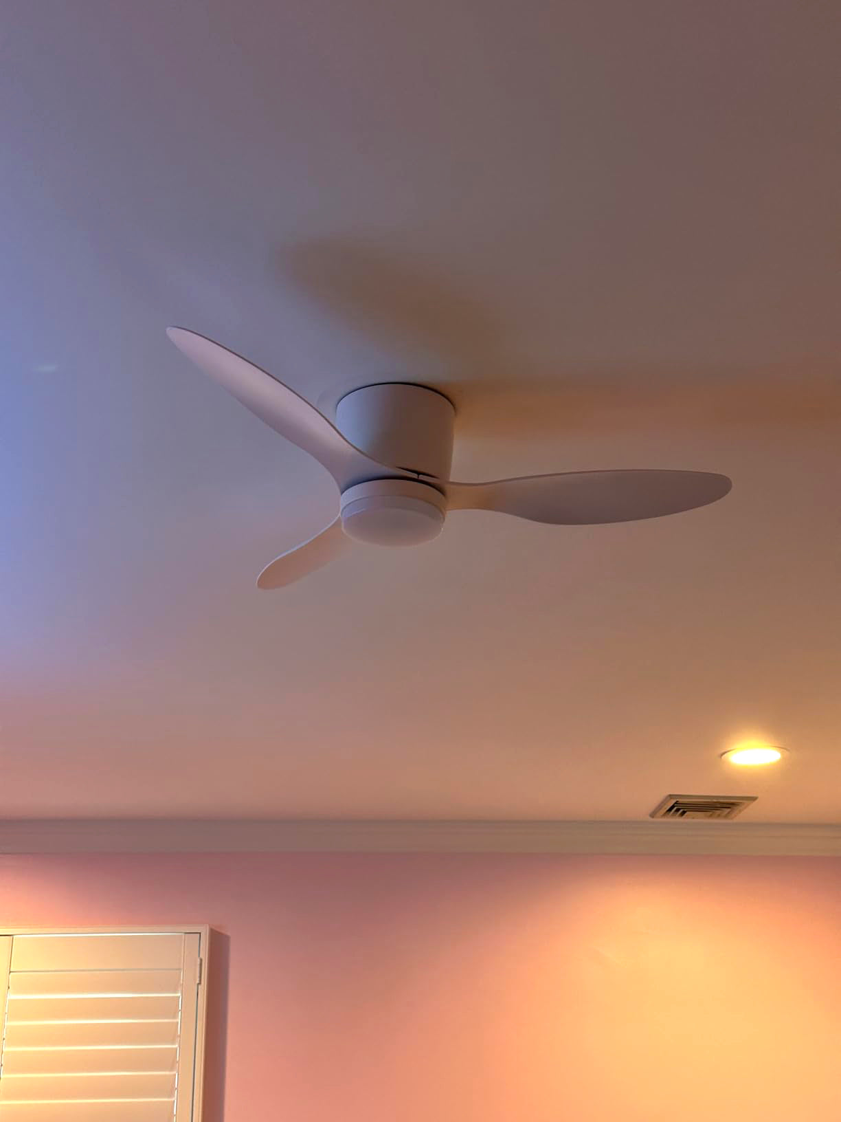 White ceiling fan under coloured room lighting