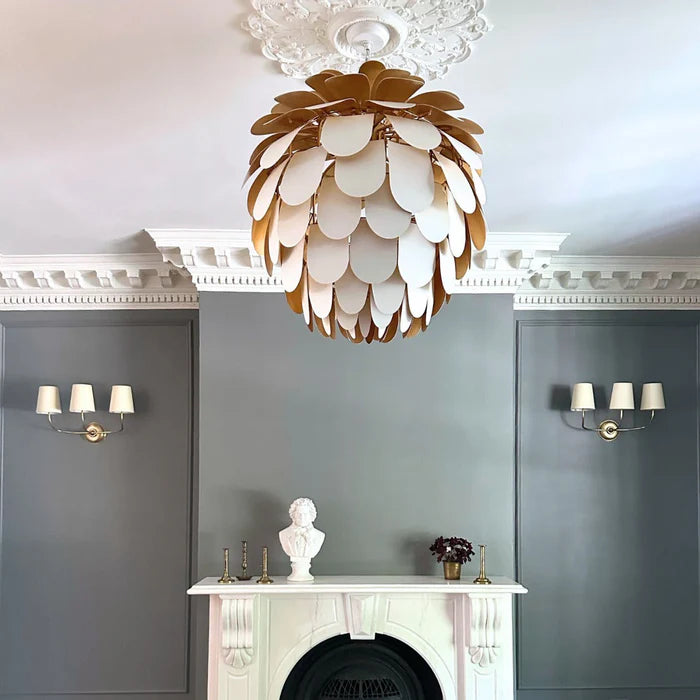 Three-shade wall lights on each side of a fireplace beneath a decorative ceiling light.