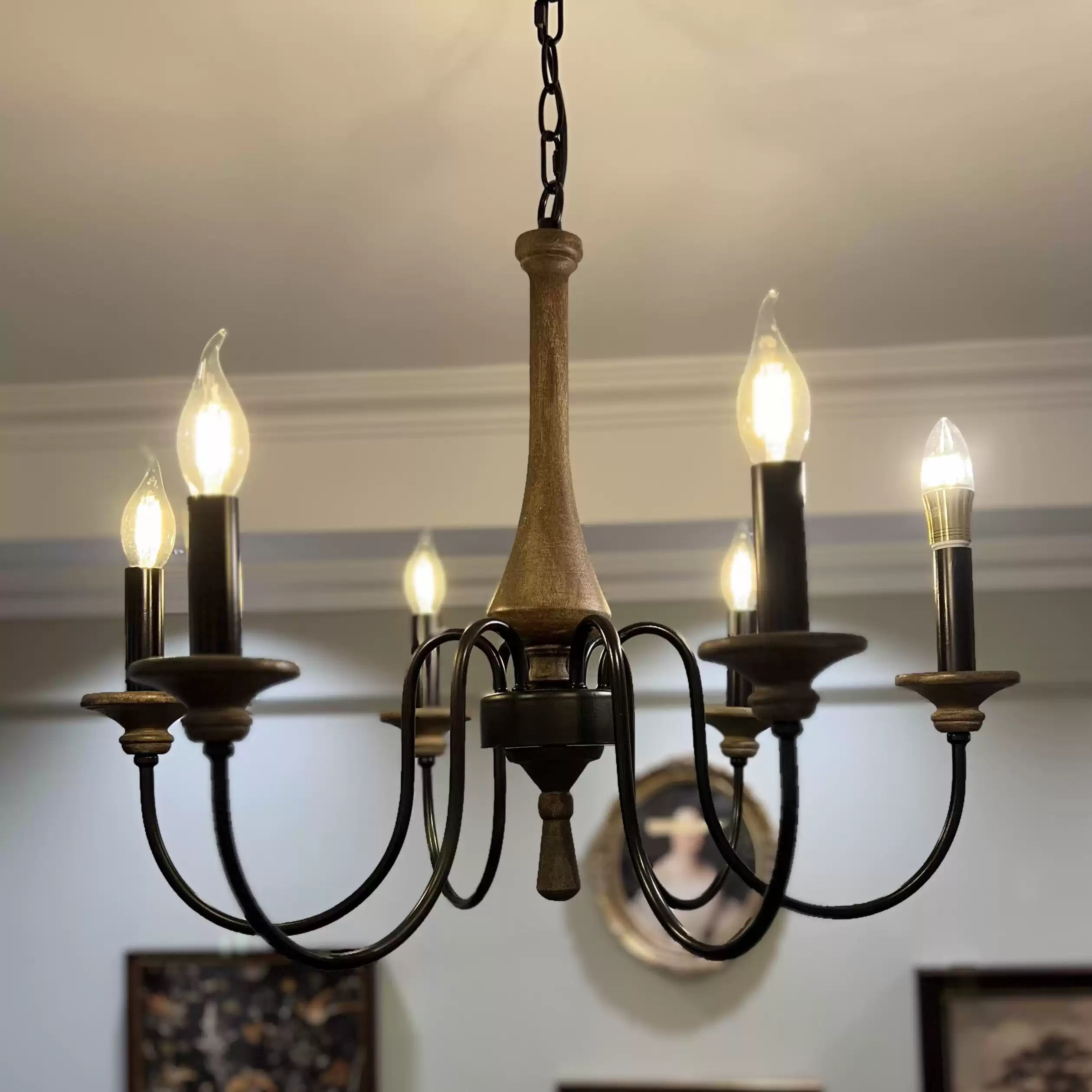 Close wood-toned central column and black curved arms with lit flame-tipped candle bulbs