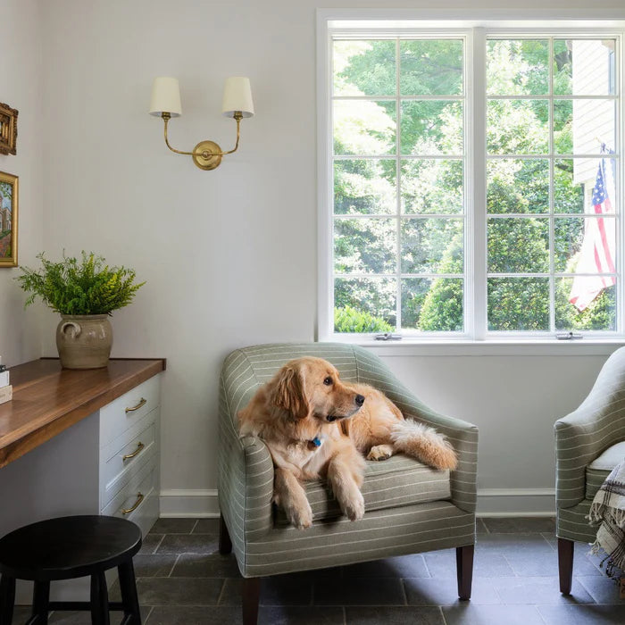 Vendome two-arm wall light beside a bright window and an armchair.