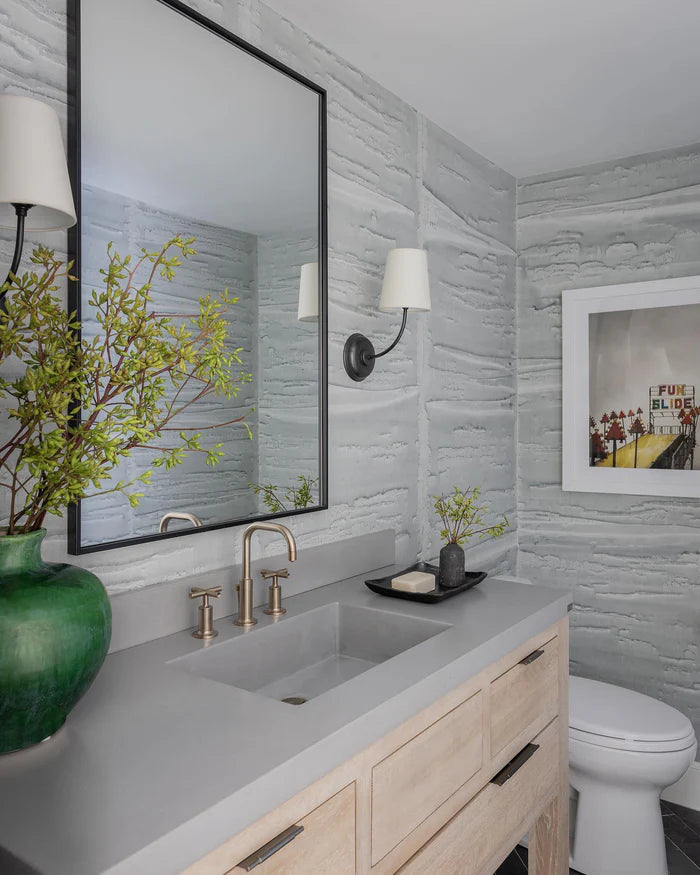 Black single-arm wall lights beside a mirror above a pale vanity.