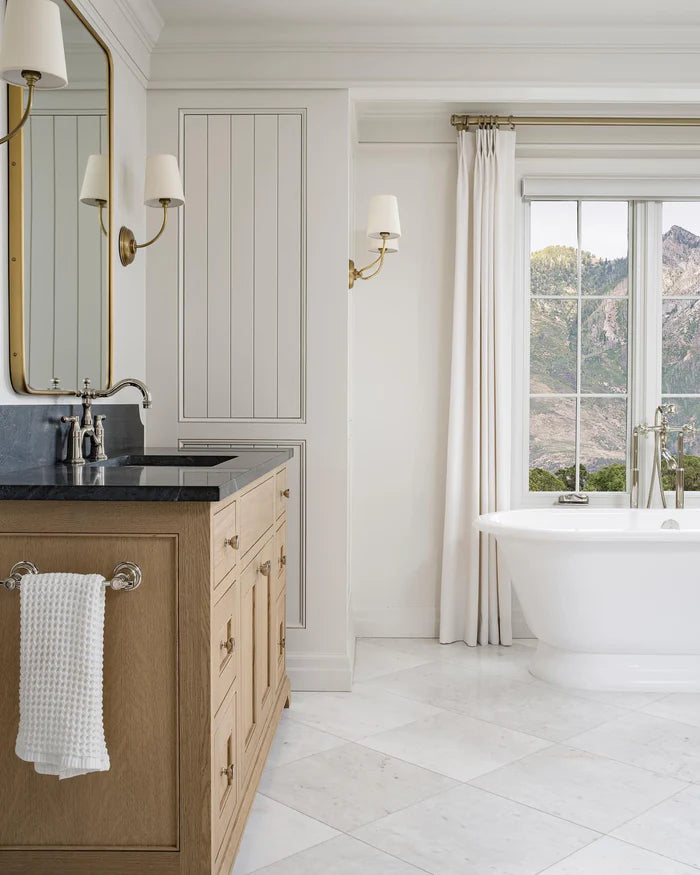 Mixed single and double brass shaded wall lights in a bright bathroom.