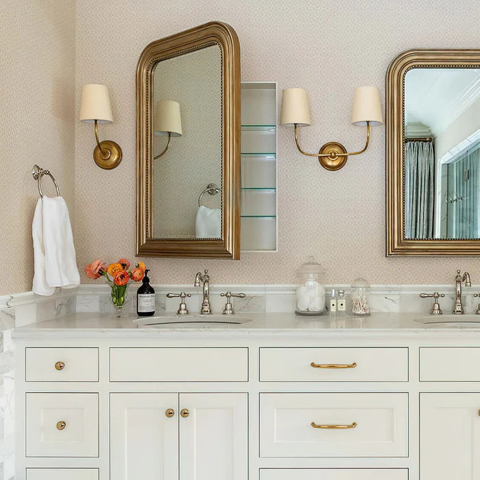 Single and double brass wall lights arranged between vanity mirrors.