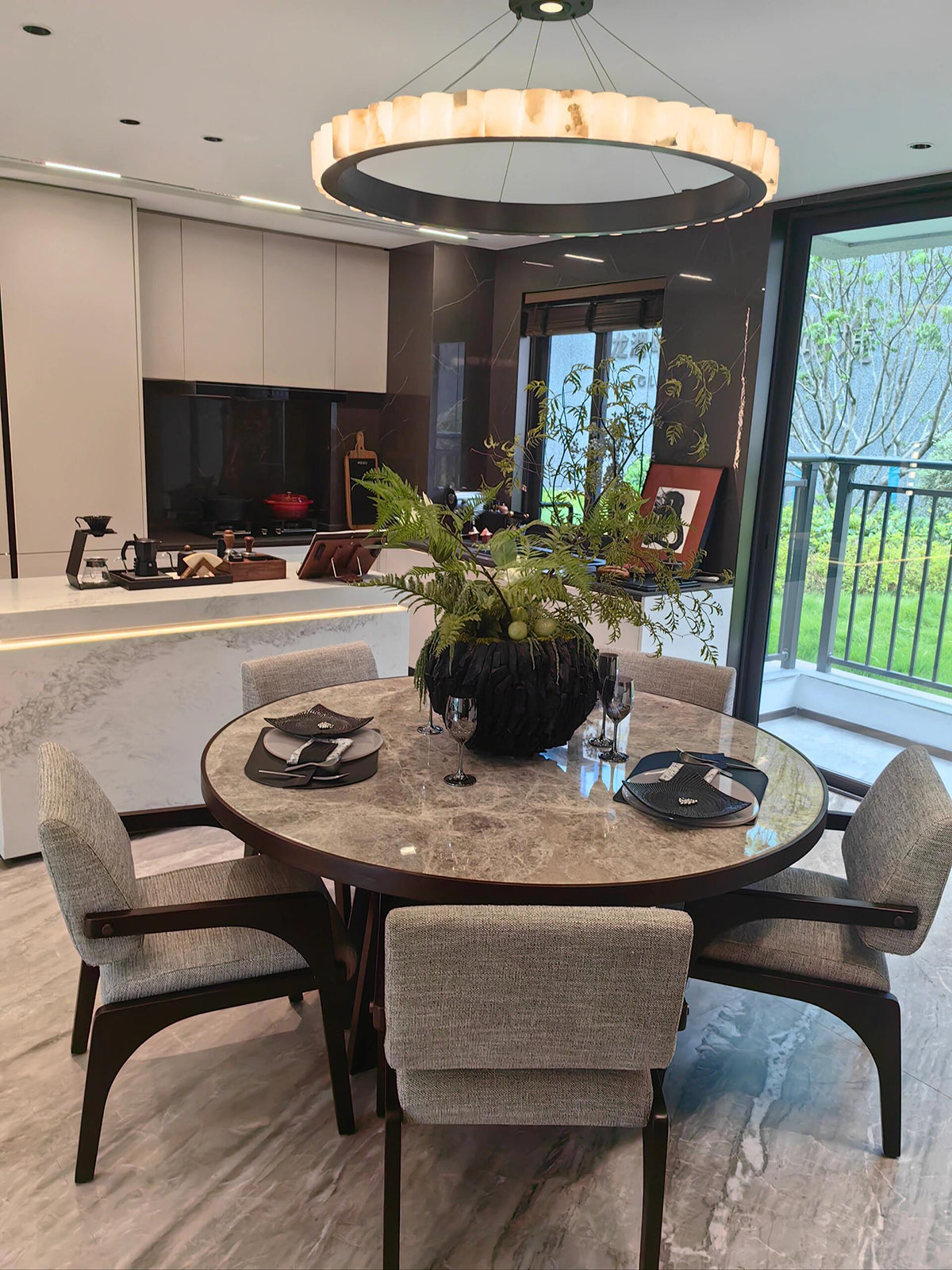 Black-band ring chandelier with veined pale segments above a round dining table near a kitchen
