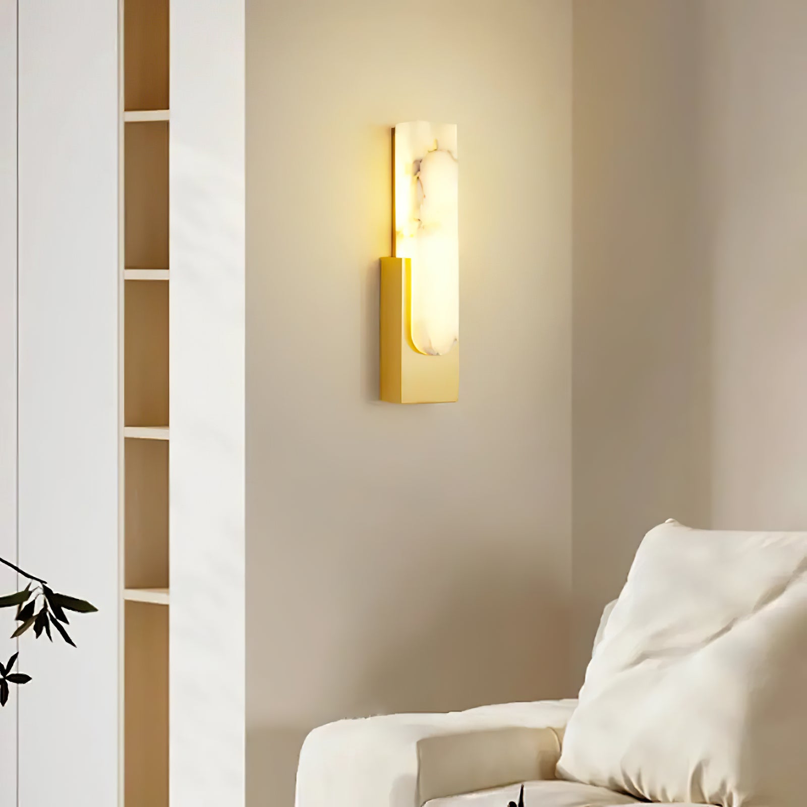 Gold wall sconce lit beside a sofa