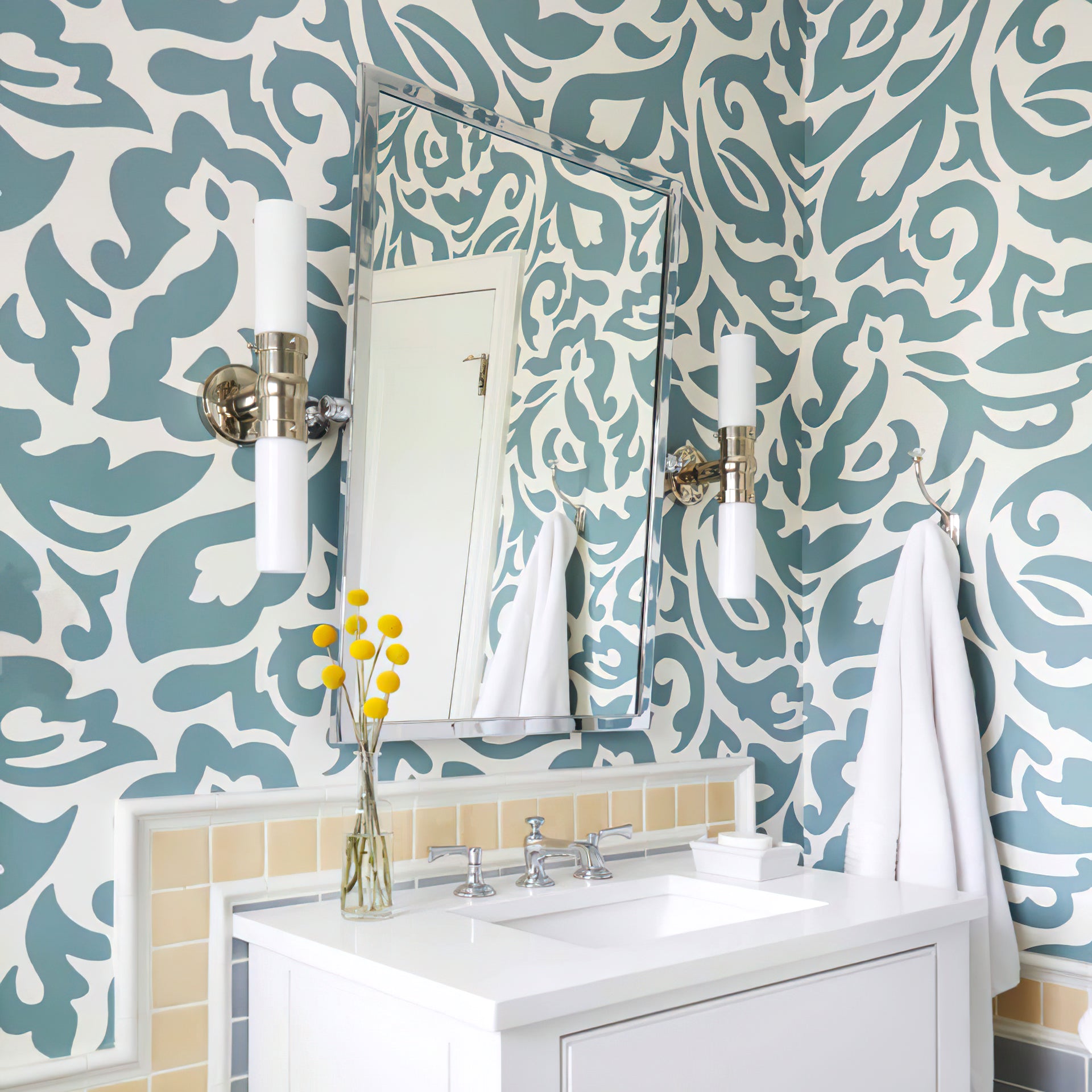 Two polished silver-tone double white-glass wall lights beside a mirror on a blue-and-white patterned wall