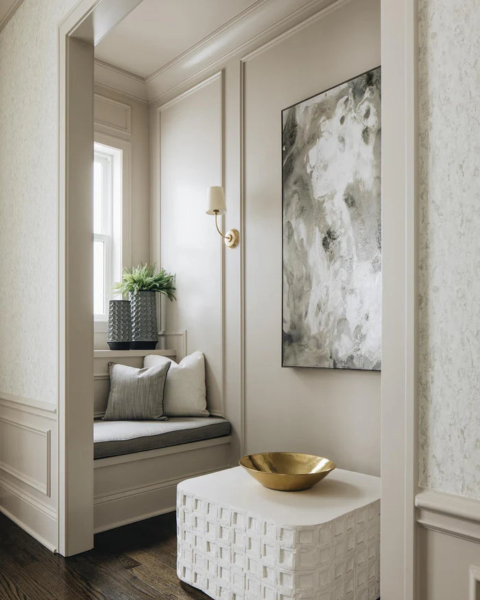 Single brass wall light near framed artwork and a window seat.